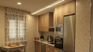 Une cuisine moderne dotée de meubles en bois, d’appareils électroménagers en acier inoxydable et d’un coin repas avec une table et des chaises.