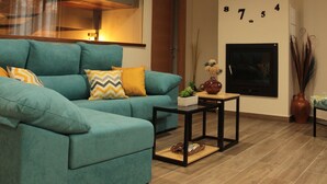 Un salon avec un canapé de couleur turquoise, une cheminée et une horloge murale.