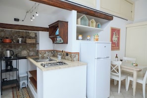 A compact kitchen with a gas stove, white refrigerator, and a small dining area with a white table and chairs. - Suite 58 · Two Ensuite Bedrooms, Sea & Old-Town Balconies, 1 Min to the Beach (Cefalù)