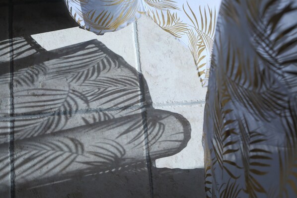 A shadow of a hand on a textured surface, possibly a wall or a piece of furniture.
