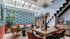 A modern living space with a staircase, a dining area, and a bookshelf.