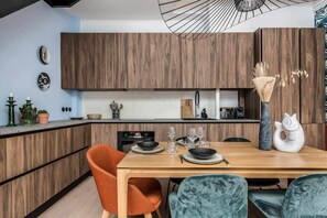 Een moderne keuken met houten kastjes, een eettafel gedekt voor vier personen en een bijzondere hanglamp.
