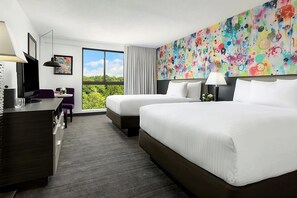 A hotel room with two beds, a desk, a chair, a TV, and a large window with a view of greenery. - Boston Getaway! 3 Spacious Units (Boston)