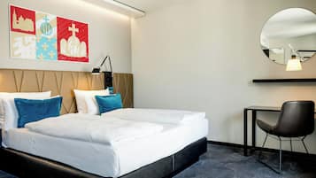 Une chambre d’hôtel avec un lit, des oreillers, un bureau, une chaise et des œuvres d’art murales.