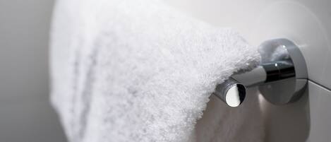 Une serviette blanche est suspendue à une barre à serviettes chromée dans une salle de bain.
