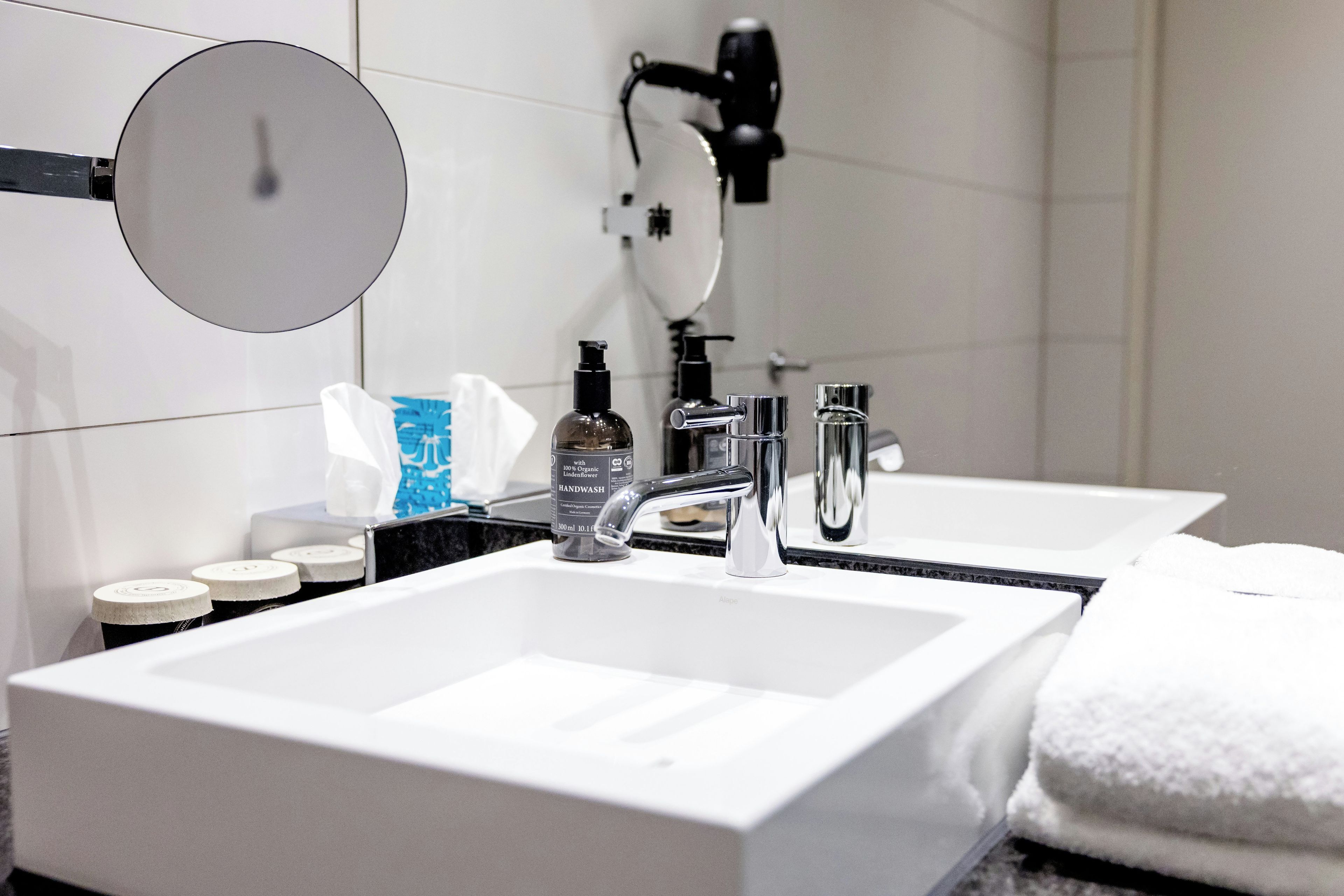 Un baño moderno con un lavamanos blanco grande, un espejo y un cabezal de ducha manual.