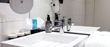 Un baño moderno con un lavamanos blanco grande, un espejo y un cabezal de ducha manual.
