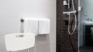 Un baño moderno con ducha, una silla blanca y un perchero.