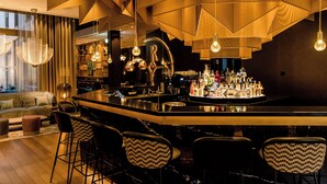 A modern bar area with a central island, bar stools, and a variety of bottles. - Motel One Aachen (Aachen)