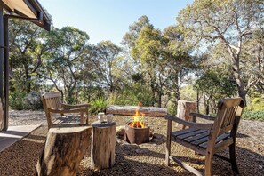 An outdoor seating area with wooden benches and a central fire pit.
