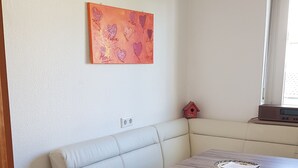 Un comedor con una mesa de madera, un sofá color beige y una pequeña decoración de un pájaro rojo.