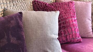 Un canapé avec quatre coussins de différentes nuances de rose et de violet.