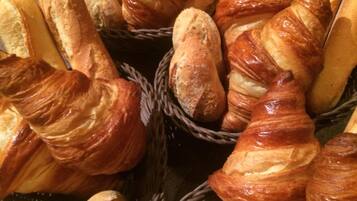 Variedad de productos horneados, como cruasanes y baguettes, exhibidos en cestas de mimbre.
