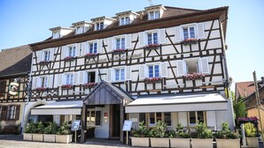 Ein traditionelles Fachwerkhäuschen mit überdachtem Eingang und Blumenkästen an den Fenstern.