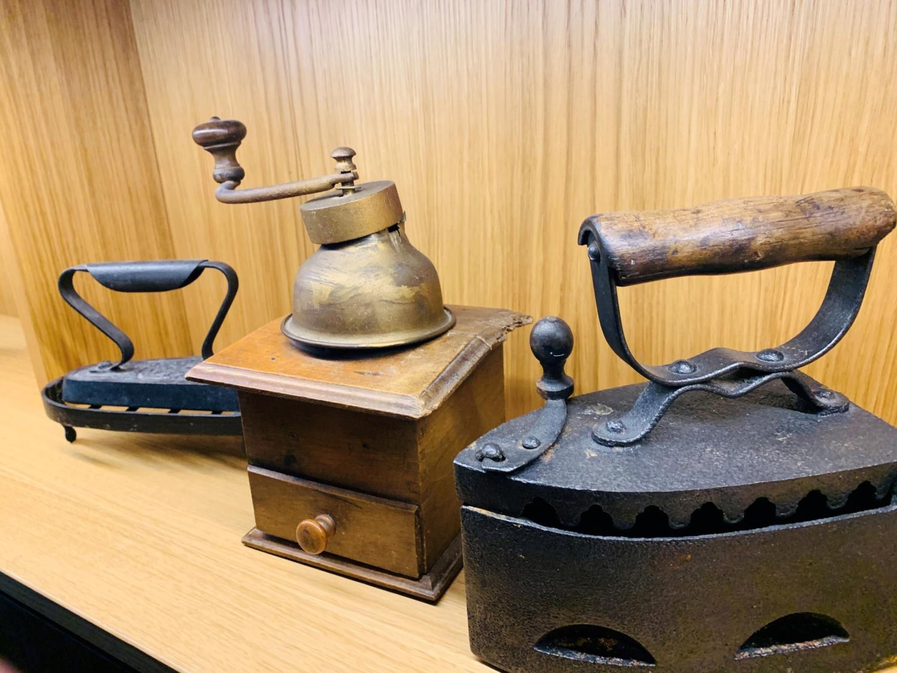 Ein altes Bügeleisen-Set mit Holzsockel und Metallgehäuse, ausgestattet mit Kurbel und Fußpedal.