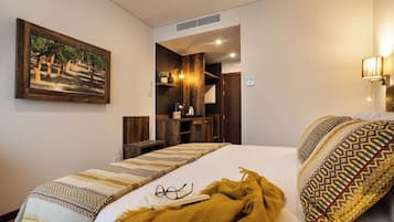 Ein Hotelzimmer mit einem Bett, einem Holz-Kopfteil, einem Bild an der Wand und einem kleinen Schreibtisch mit einer Lampe.