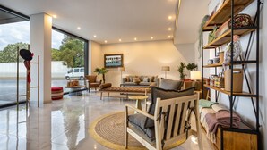 Una sala de estar moderna con un ventanal grande, un conjunto de sofás, una mesa de centro y una estantería.