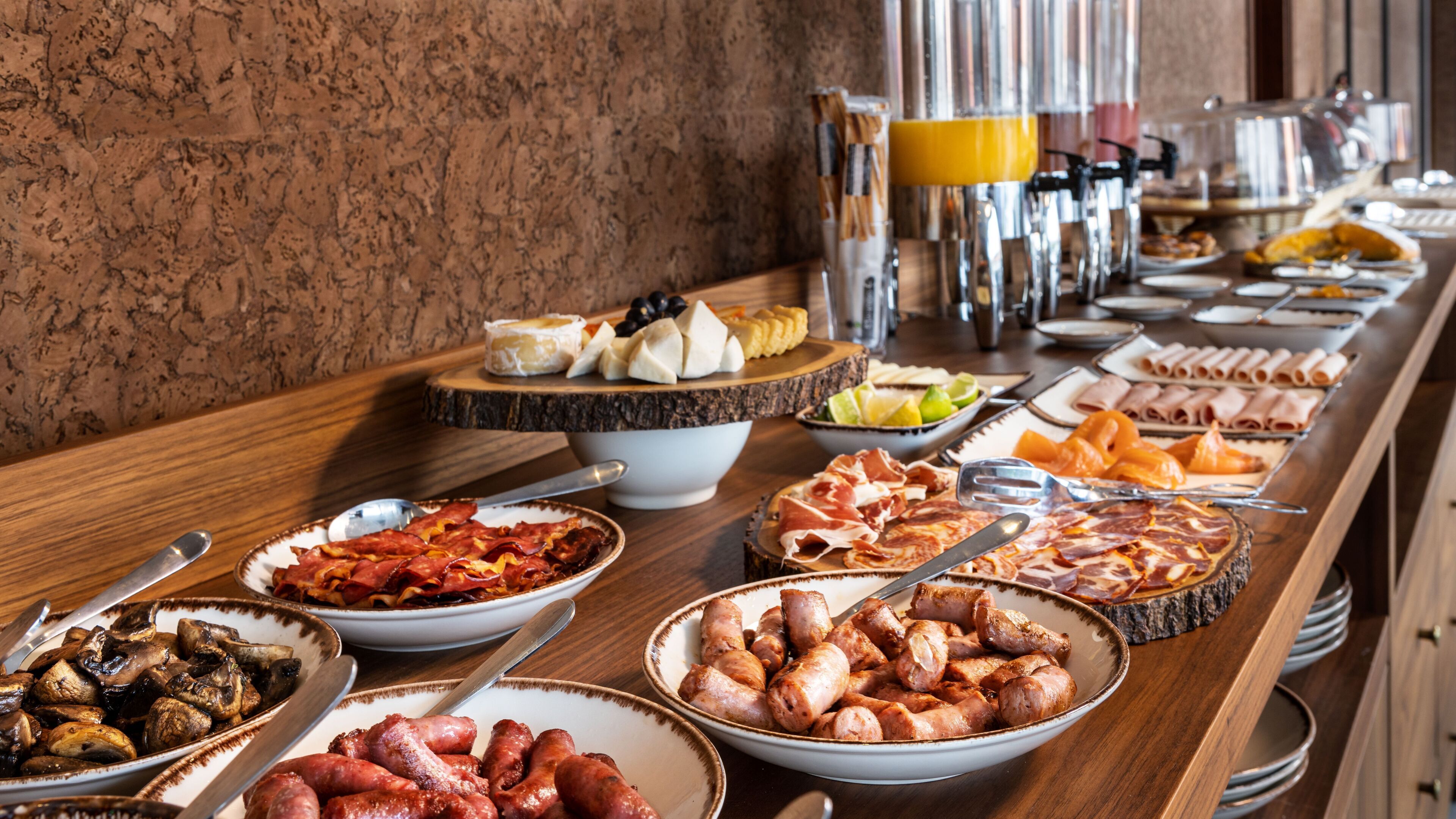 A buffet with various food items including meats, cheeses, and fruits.
