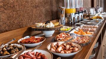 A buffet with various food items including meats, cheeses, and fruits.