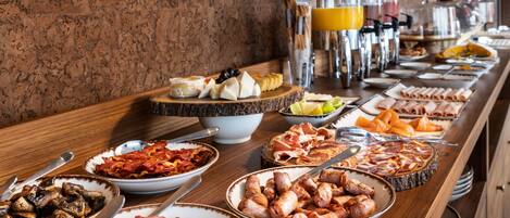 A buffet with various food items including meats, cheeses, and fruits.