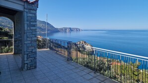 A stone balcony with a metal railing overlooking a coastal sea view.
