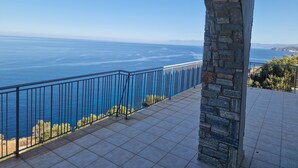 Ein Balkon mit einer Steinsäule, einem Kachelboden und Blick aufs Meer.