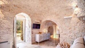 Una habitación de paredes de piedra con una televisión, un armario y un sofá.