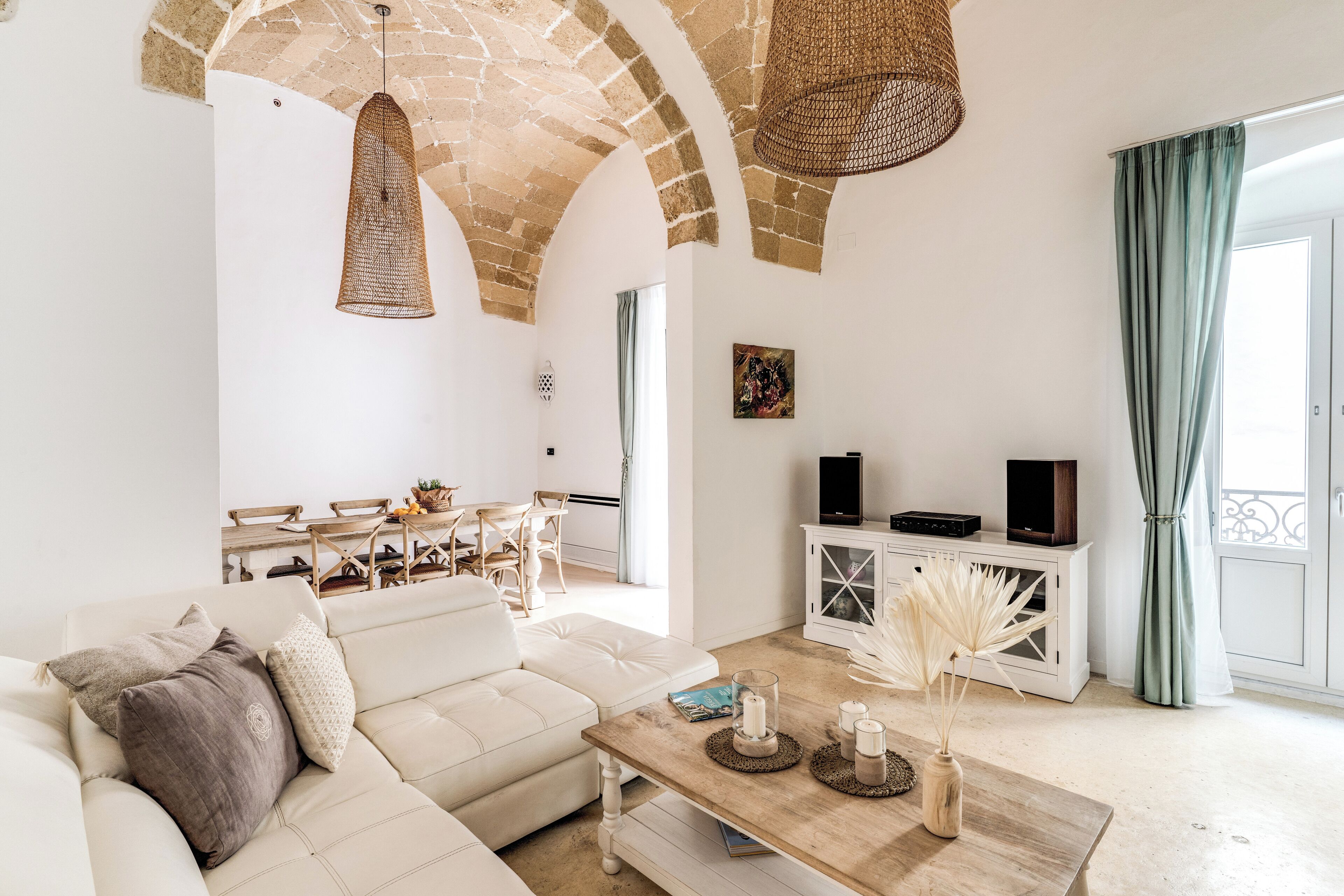 Ein geräumiges Wohnzimmer mit einem weißen Sofa, einem Holztisch und einer Decke aus Steinbögen.