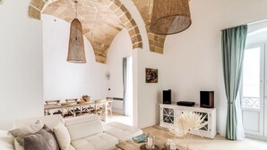 A spacious living room with a white sofa, a wooden coffee table, and a stone arch ceiling.