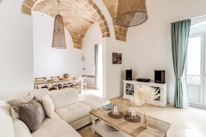 Un soggiorno con un divano bianco, un tavolino in legno, un mobile TV e un'area pranzo con sedie e tavolo.