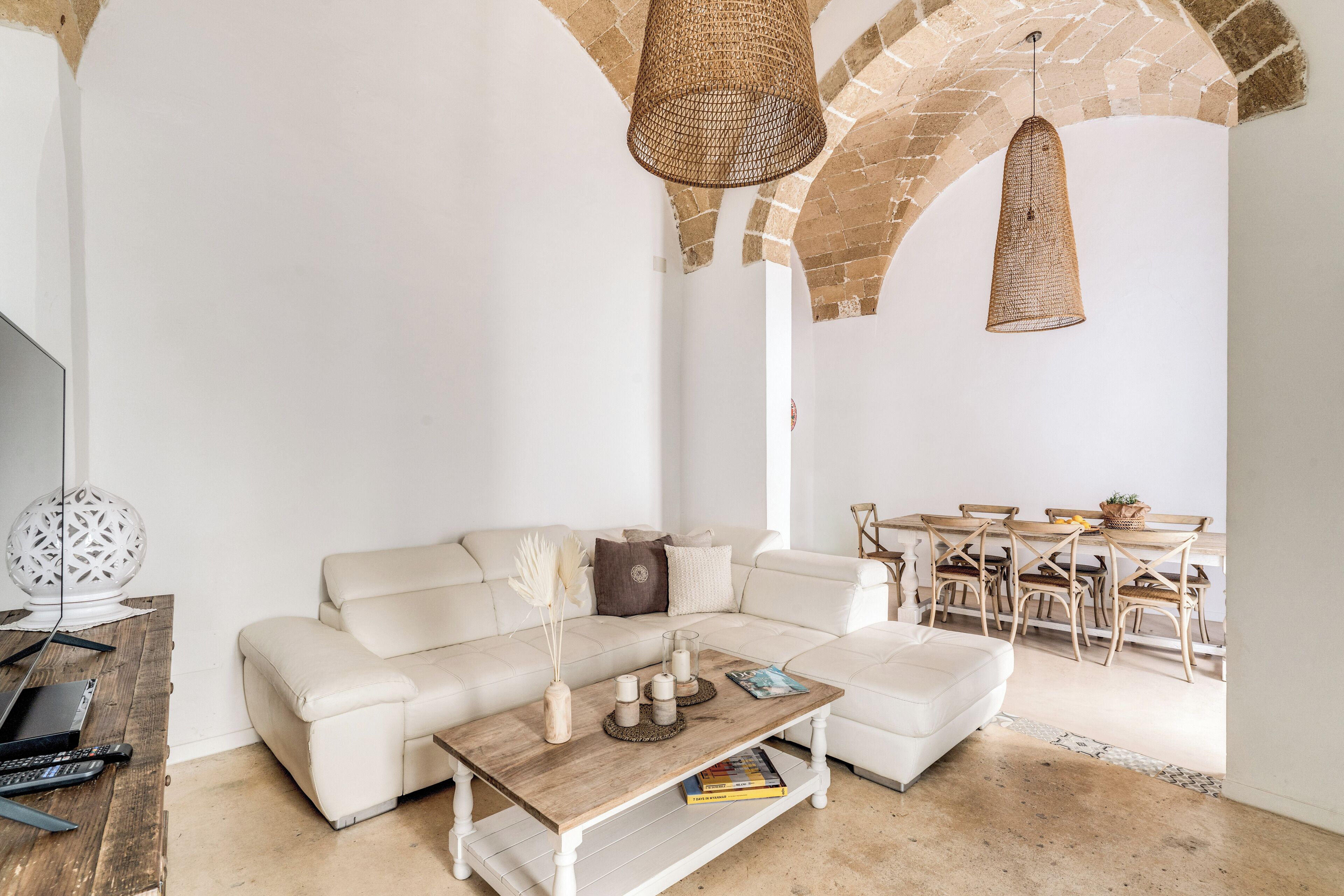 Ein modernes Wohnzimmer mit einem weißen Sofa, einem Holztisch und einem Essbereich mit Tisch und Stühlen.