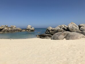 A beach with large rocks and clear blue water.