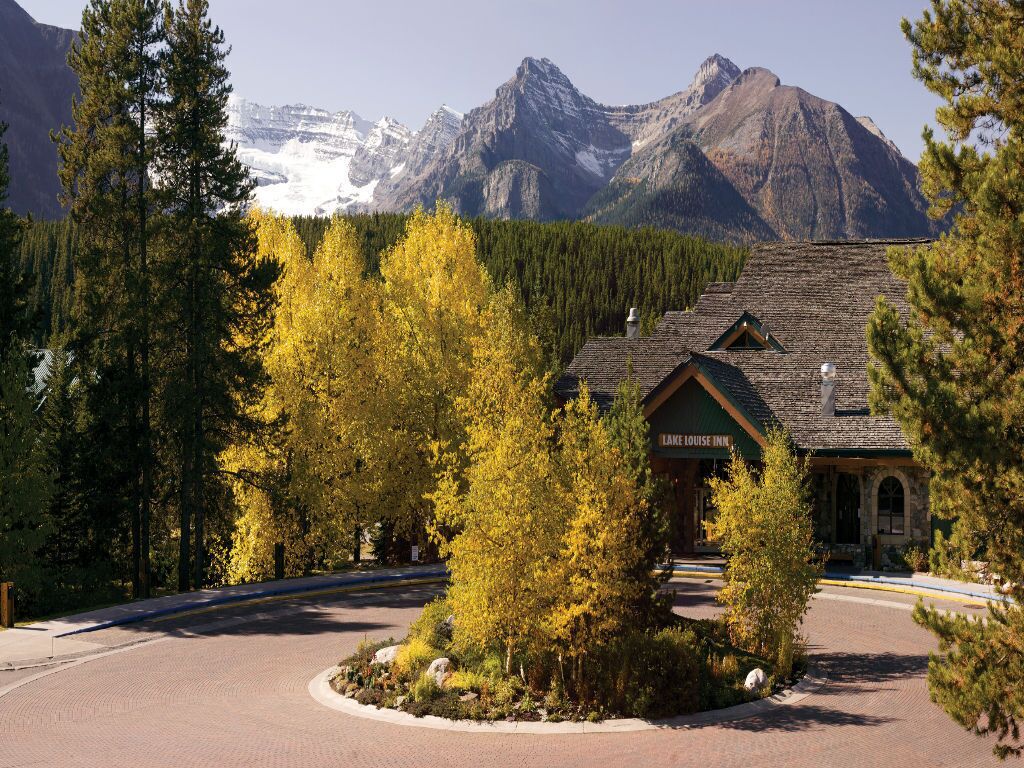 Arrive at the charming entrance framed by vibrant autumn colors and majestic mountains.