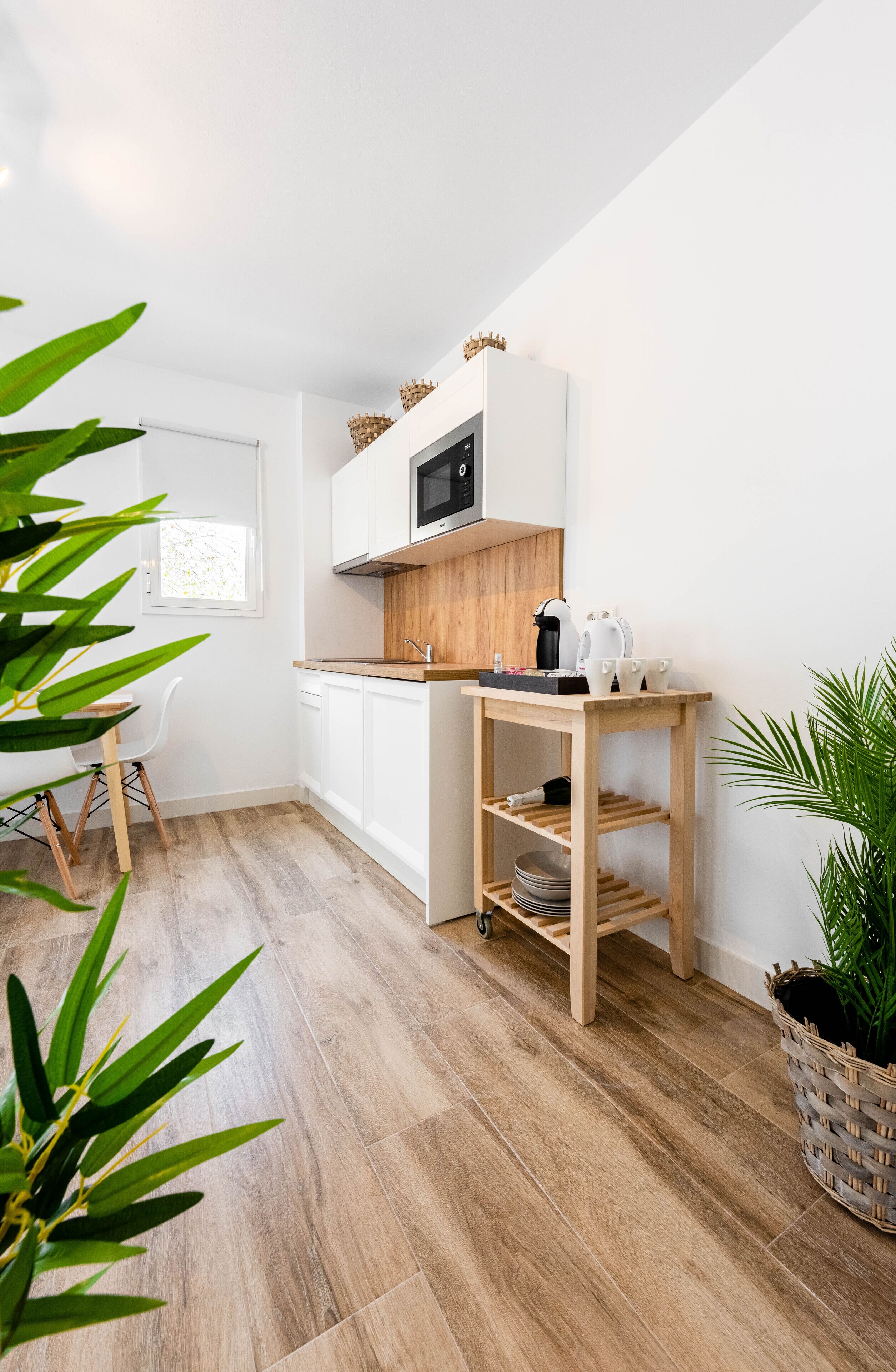 Eine moderne Küche mit weißen Schränken, einer Mikrowelle und einer Holz Arbeitsplatte.