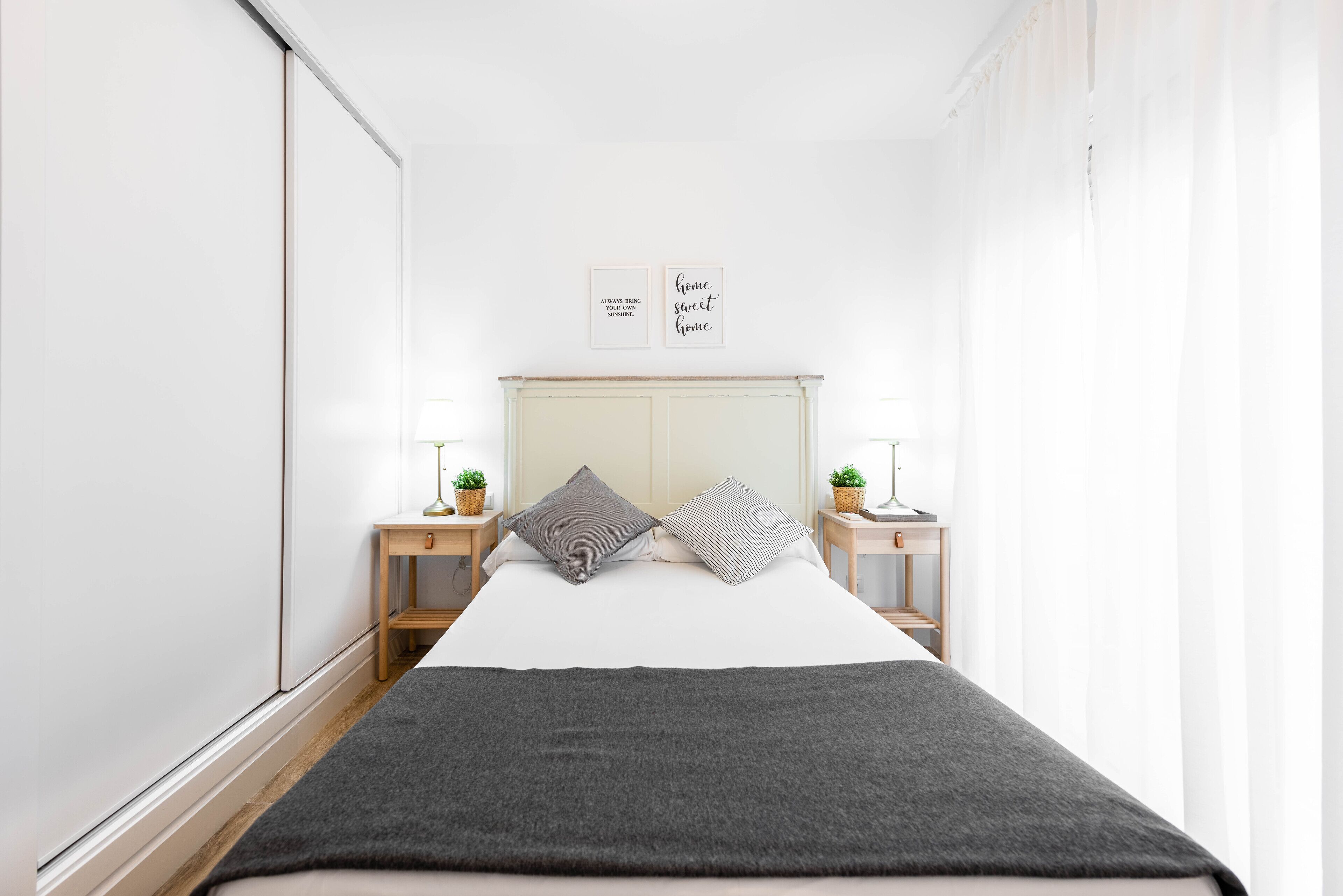 Un dormitorio minimalista con cama, mesitas de noche y decoración en la pared.