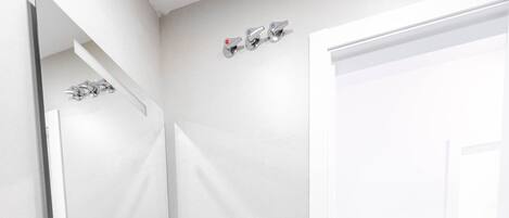 A modern bathroom with a white sink, wooden vanity, and a large mirror.