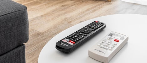 Una sala de estar con un televisor mostrando 'NETFLIX' en la pantalla, un control remoto y una mesa de centro blanca.