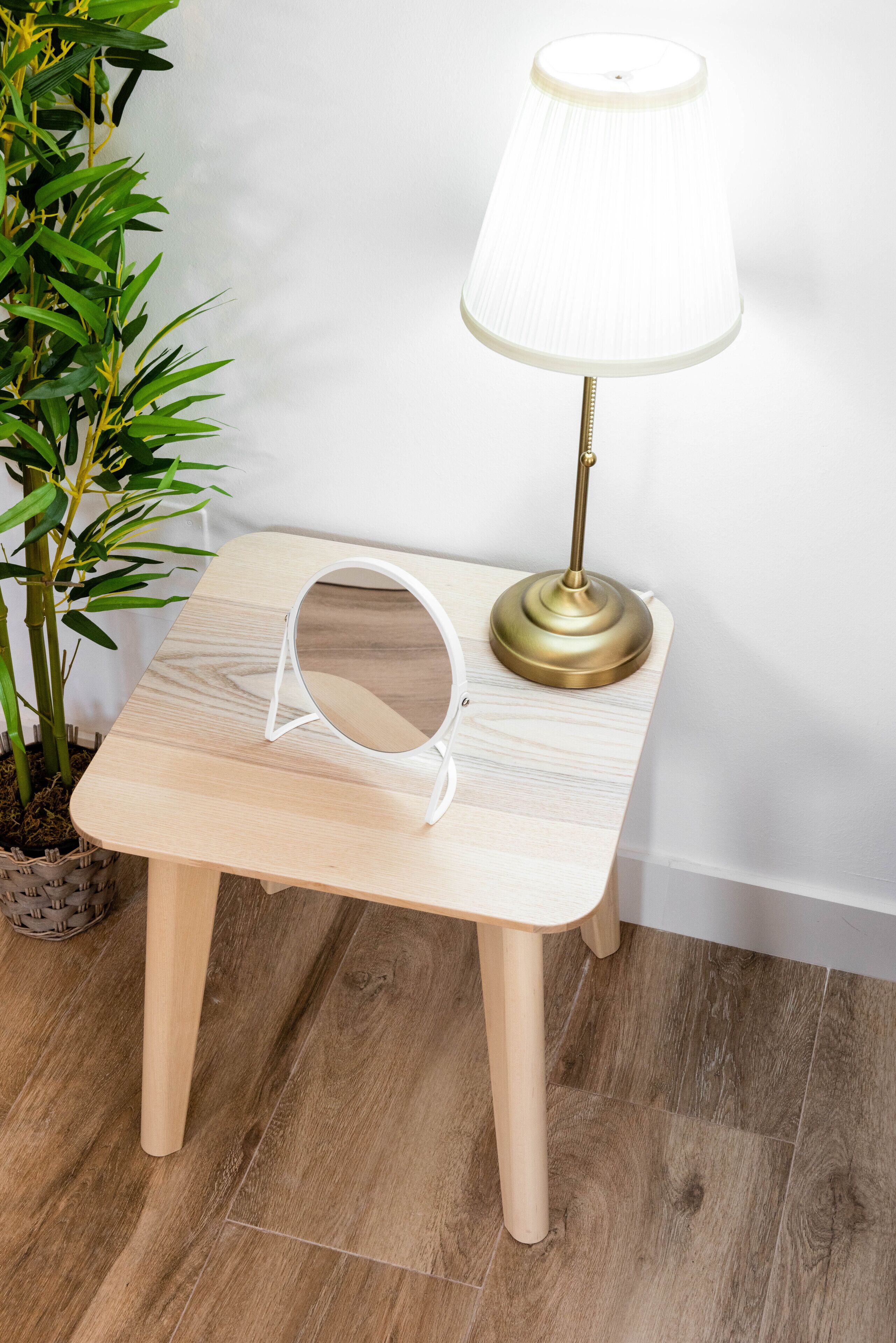 Une petite table en bois, avec une lampe et un miroir.
