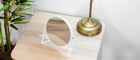 A small wooden table with a lamp and a mirror.