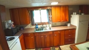 A compact kitchen with wooden cabinets, a sink, a stove, and a refrigerator. - The Lodge in Manistee (Manistee)