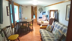 A living room with a plaid sofa, wooden dining table, and chairs. - The Lodge in Manistee (Manistee)