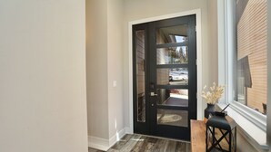 A modern entryway with a dark wooden door, a wooden floor, and a small table with a black lantern. - Hot Tub, Modern Home, Hiking and Fishing Close! (Durango)