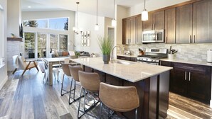 A modern kitchen with a large island, dark wood cabinets, stainless steel appliances, and a view to the outdoors. - Hot Tub, Modern Home, Hiking and Fishing Close! (Durango)