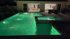 A swimming pool area with a glass enclosure and a patio with outdoor seating.