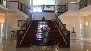 A spacious lobby with a grand staircase, a decorative table, and a vase of flowers.
