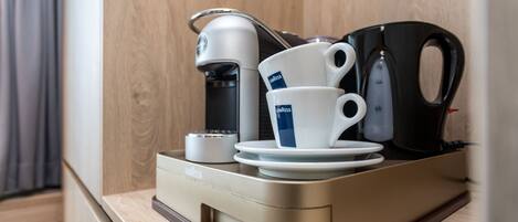 Une machine à café, une tasse et une bouilloire sur un plan de travail.