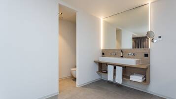 Un baño moderno con un espejo grande, un lavabo blanco y un mueble de tocador de madera.