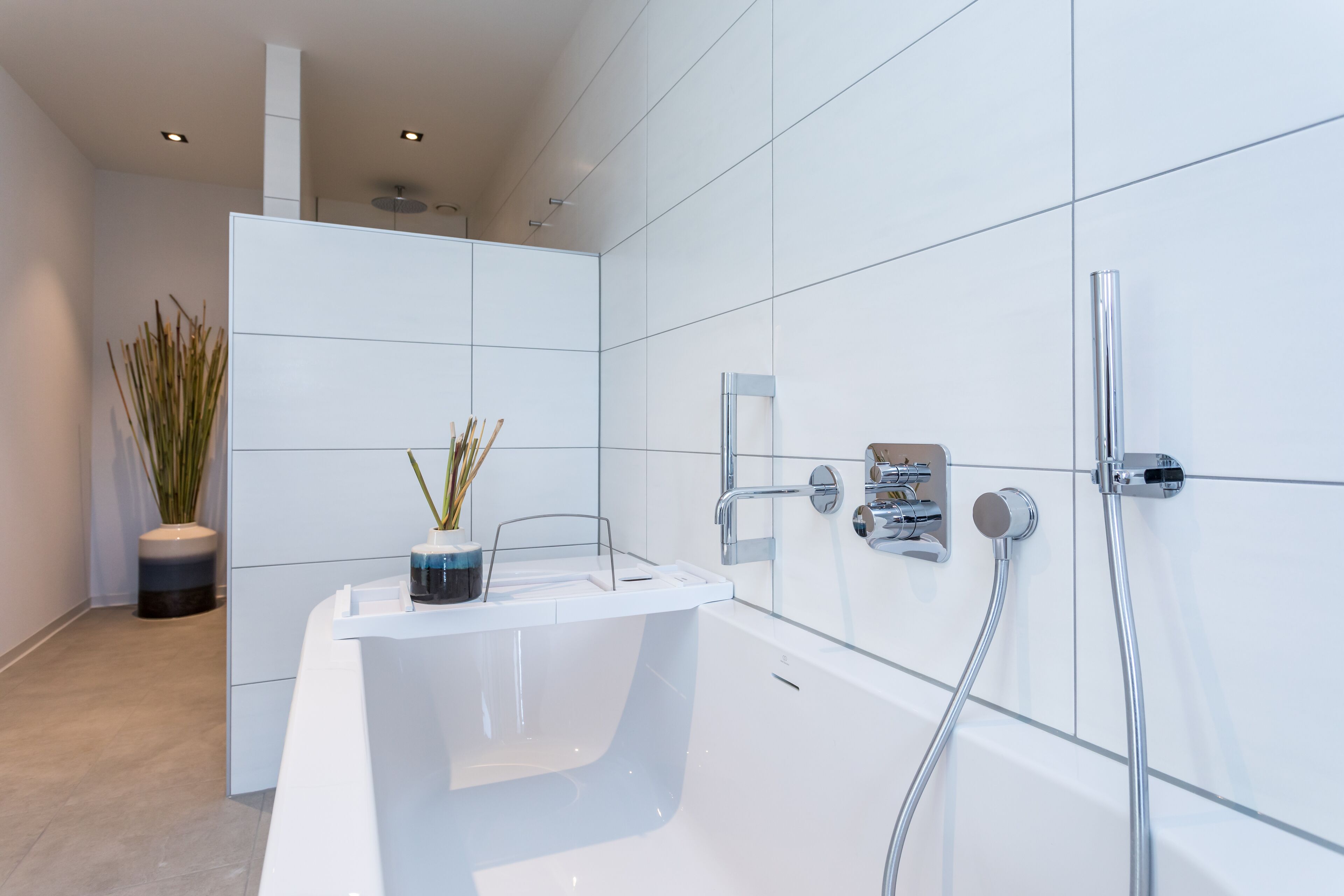 Een moderne badkamer met een vrijstaand bad, douchetuit en een kraan op de muur.
