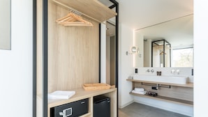 Un baño moderno con tocador de madera, refrigerador negro y un espejo grande.