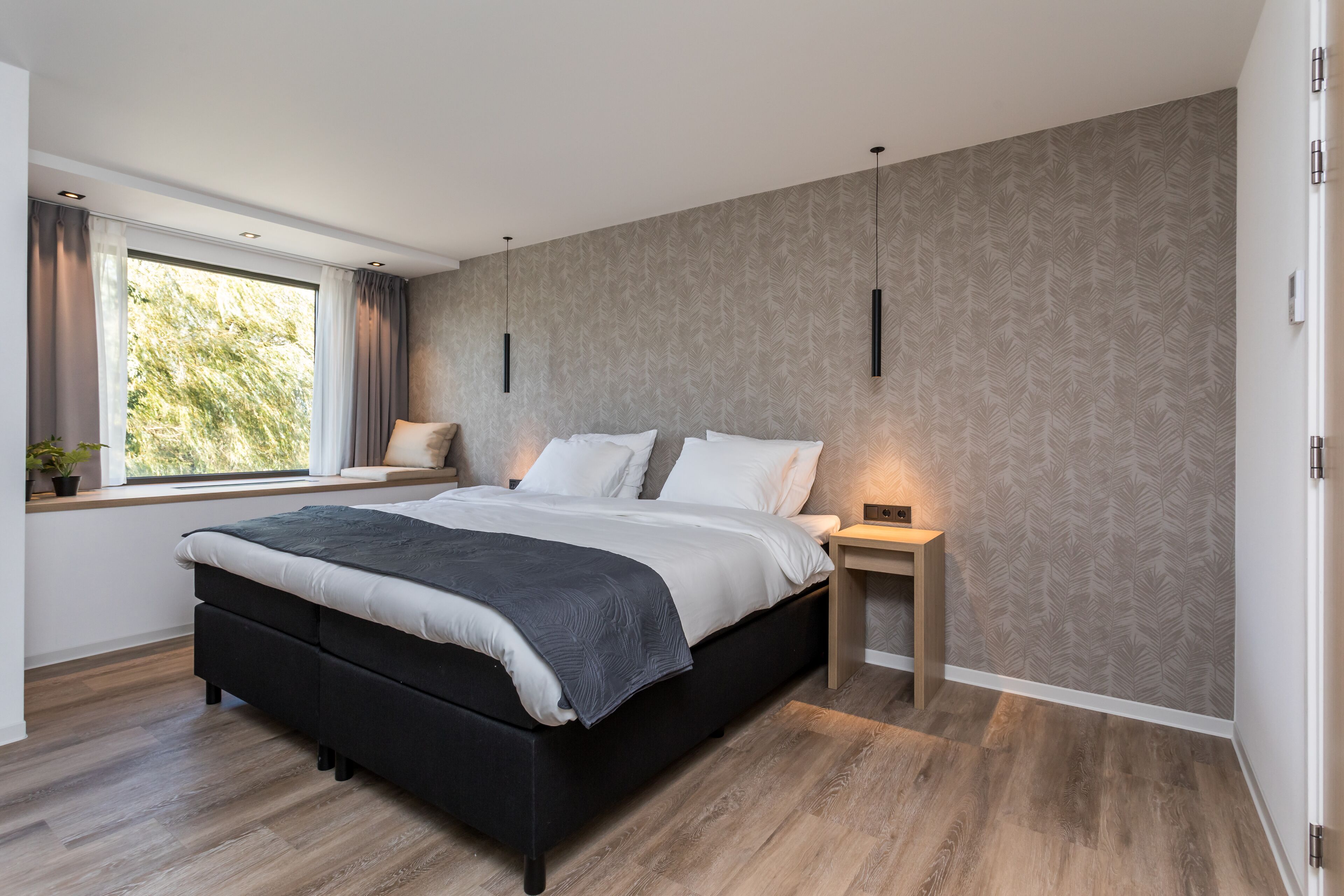 Un dormitorio moderno con una cama grande, una mesita de noche y una ventana con cortinas.